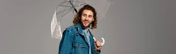 Pohledný Usmívající Muž Džínové Bundě Drží Deštník Izolovaný Šedé — Stock fotografie