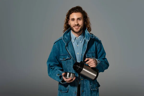 Hombre Sonriente Elegante Chaqueta Mezclilla Sosteniendo Termos Aislados Gris —  Fotos de Stock