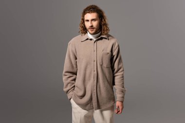 Gri gömlekli yakışıklı adam kameraya bakıyor. 