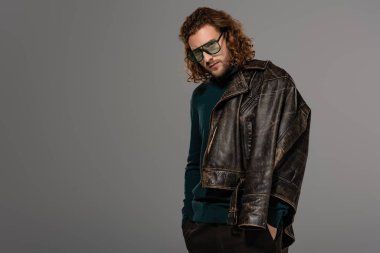 Gri renkli kameraya bakan deri ceketli yakışıklı adam.