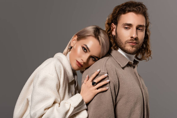 Женщина в белом халате обнимает красивого мужчину в рубашке, изолированной от серого
