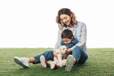 smiling mother and son looking at Havanese puppy isolated on white