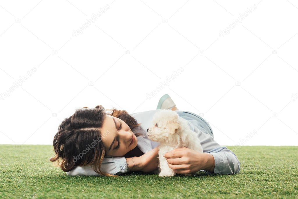 woman looking at Havanese puppy and lying on grass isolated on white