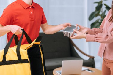 Termal çantalı kurye görüntüsü iş kadınına yiyecek kabı veriyor. 