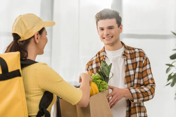 Selective Focus Courier Yellow Uniform Giving Package Fresh Vegetables Smiling — Stock Photo, Image