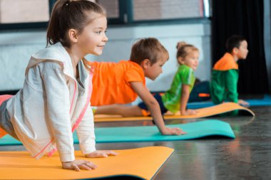 Yoga minderleri üzerinde asana yapan çok kültürlü çocukların seçici odak noktası