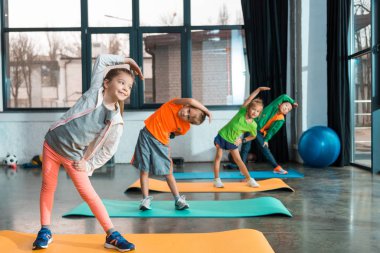 Çok kültürlü çocukların seçici odağı spor merkezindeki spor minderlerinde ısınıyor.