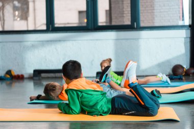 Spor salonundaki spor paspasların üzerine uzanan çocukların seçici odak noktası