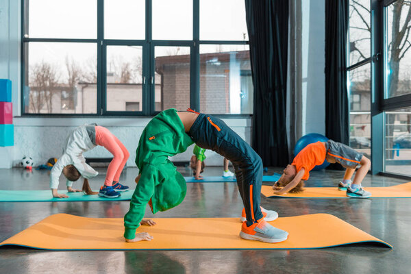 Селективное внимание детей, делающих гимнастический мост на фитнес-ковриках
