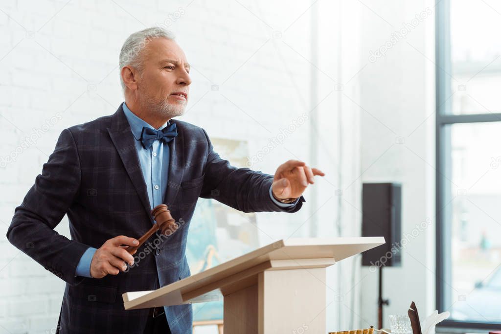 auctioneer holding gavel and pointing with finger during auction