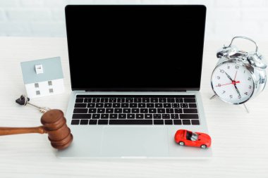 wooden gavel, models of car and house, key, laptop, alarm clock on table  clipart