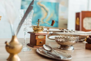 selective focus of coffee grinder, glass, ashtray and ancient plate with cutlery clipart