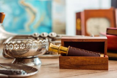 selective focus of spyglass in box and ancient ashtray on table  clipart