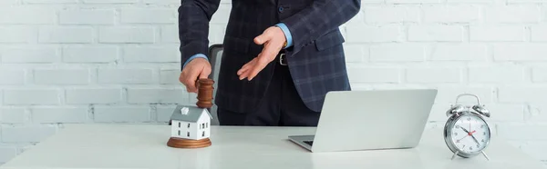 家の模型を手で指差している競売人のパノラマ写真です — ストック写真