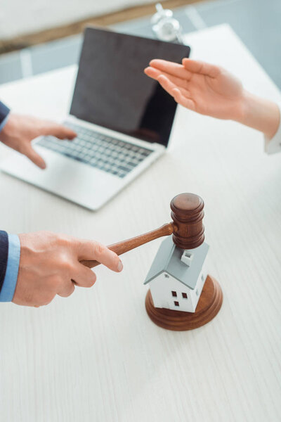 cropped view of auctioneer hitting with gavel model oh house and woman pointing with hand 
