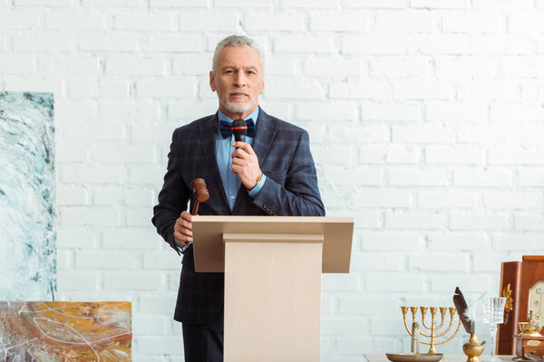 аукционист разговаривает с микрофоном и держит молоток во время аукциона
