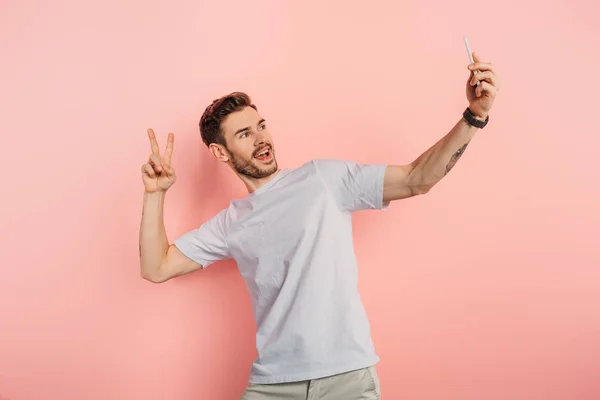 Ενθουσιασμένοι Νεαρός Δείχνει Χειρονομία Νίκης Ενώ Λήψη Selfie Στο Smartphone — Φωτογραφία Αρχείου