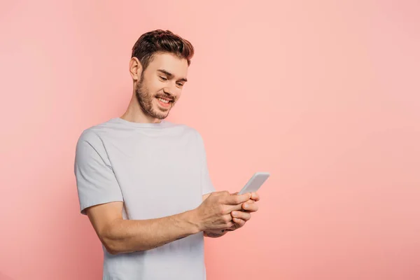 Gelukkig Jonge Man Chatten Smartphone Roze Achtergrond — Stockfoto