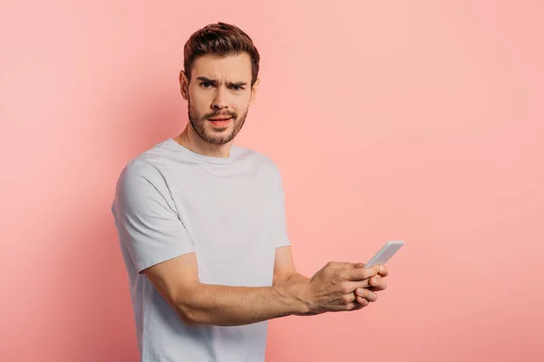 Shocked Young Man Looking Camera While Chatting Smartphone Pink Background — Stockfoto