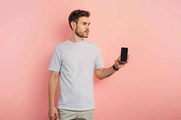 Zelfverzekerde Jonge Man Toont Smartphone Met Leeg Scherm Weg Kijken — Stockfoto