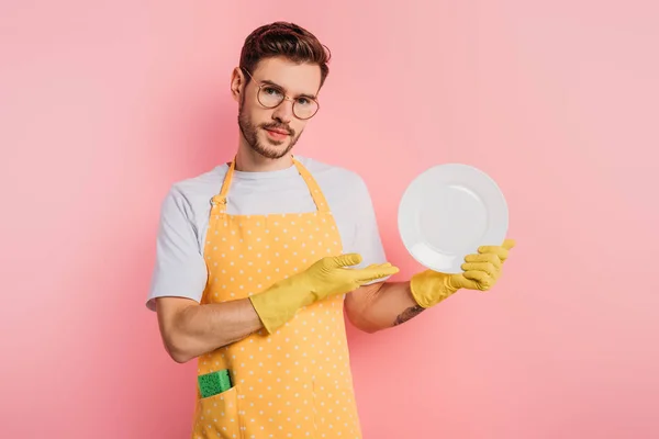 Confident Young Man Apron Rubber Gloves Showing Clean Plate Pink — Stock Photo, Image