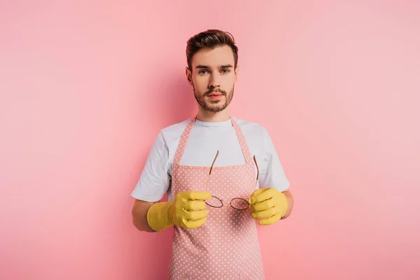 Serious Young Man Apron Rubber Gloves Holding Glasses Pink Background — Stock Photo, Image