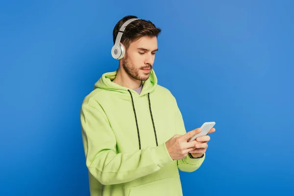 Attentive Young Man Wireless Headphones Using Smartphone Isolated Blue — Stock Photo, Image