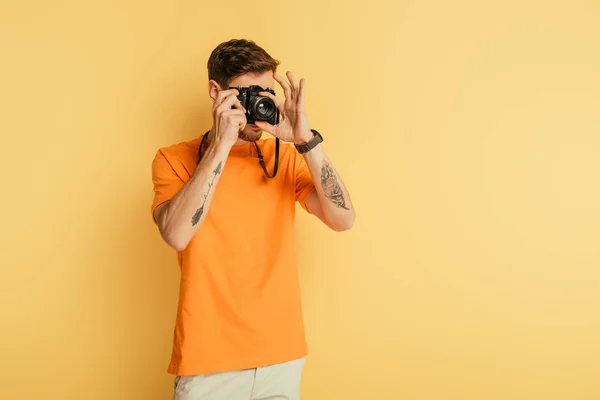 Young Tattooed Photographer Taking Picture Yellow Background — Stockfoto