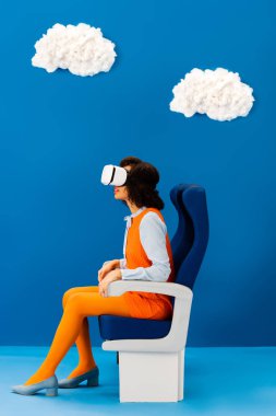 VR kulaklıklı Afro-Amerikan 'ın mavi arka planda oturan bulutlu görüntüsü 