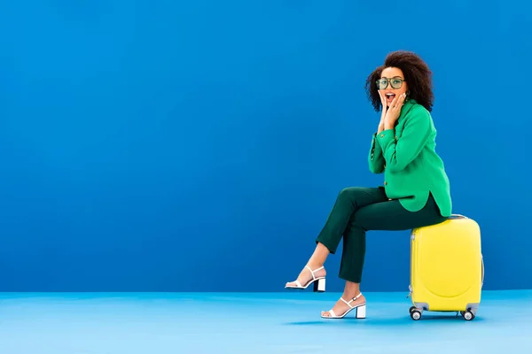 Chocado Africano Americano Mulher Sentado Saco Viagem Fundo Azul — Fotografia de Stock