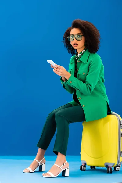 Shocked African American Woman Sitting Travel Bag Holding Smartphone Blue — Stock Photo, Image