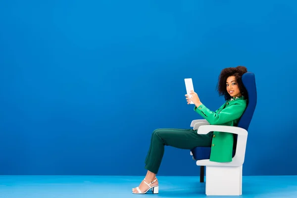 Sonriente Mujer Afroamericana Sentada Asiento Sosteniendo Tableta Digital Sobre Fondo — Foto de Stock