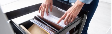 Cropped view of businesswoman searching dossier in paper folders in cabinet driver, panoramic shot