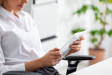 Cropped view of businesswoman using digital tablet in office 