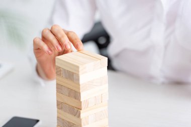 Selective focus of businesswoman playing blocks wood tower game at table 
