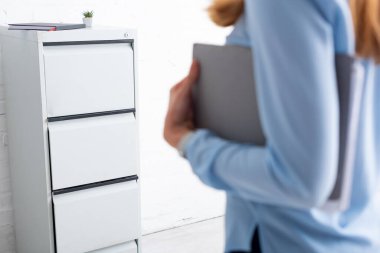 Selective focus of cabinet driver and businesswoman holding paper folder in office