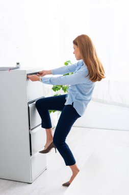 Side view of businesswoman trying to opening cabinet driver in office clipart