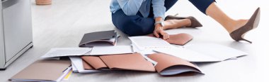 Cropped view of businesswoman sitting on floor with documents, panoramic shot