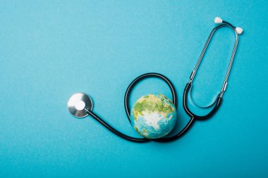 Top view of globe and stethoscope on blue background, world health day concept clipart