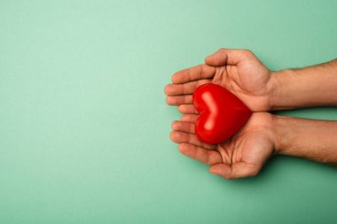 Yeşil arka planda dekoratif kırmızı kalbi olan bir adamın dünya sağlık günü konsepti.