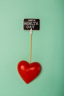 Top view of decorative red heart and card with world health day lettering on green background clipart