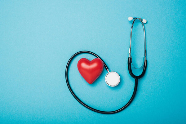 Вид сверху на декоративное сердце и стетоскоп на синем фоне, концепция Всемирного дня здоровья
