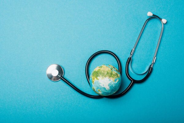 Top view of globe and stethoscope on blue background, world health day concept