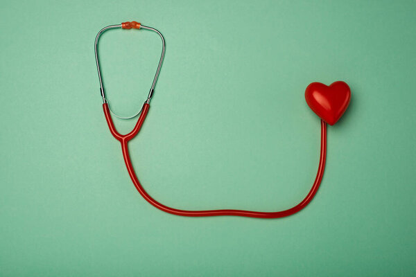 Top view of stethoscope and decorative red heart on green background, world health day concept