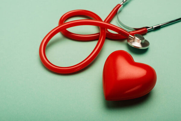 Stethoscope and red heart on green background, world health day concept