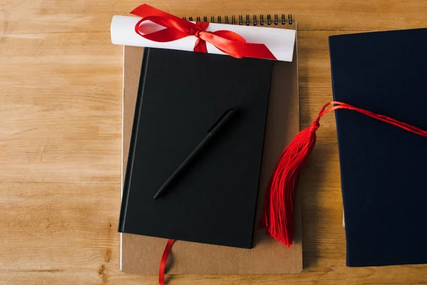 Κάτοψη Των Notebook Στυλό Δίπλωμα Και Κόκκινη Φούντα Ξύλινο Φόντο — Φωτογραφία Αρχείου