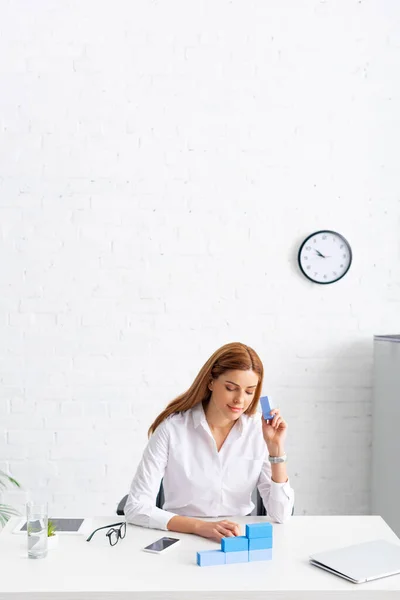 Businesswoman making marketing pyramid from blue building blocks near gadgets on table — Stock Image Businesswoman Making Marketing Pyramid Blue Building Blocks Gadgets Table Royalty Free Stock Images