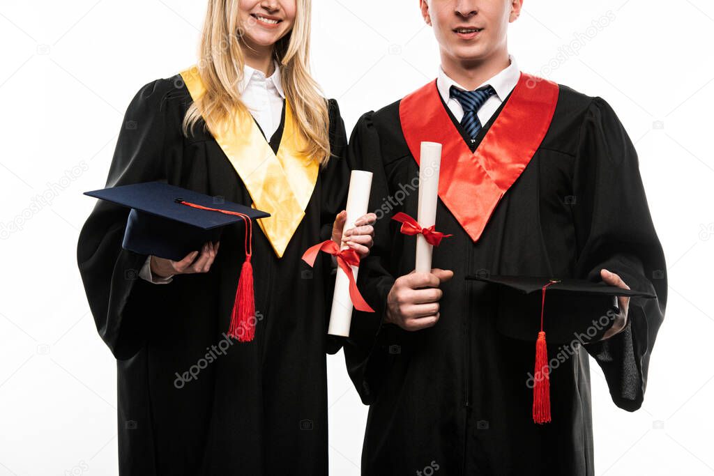 Front view of students holding graduation caps and diplomas isolated on white