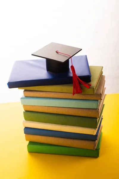 Capa Graduação Com Borla Vermelha Cima Livros Superfície Amarela Fundo — Fotografia de Stock