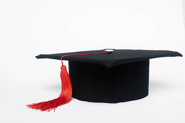 黒卒業キャップとともに赤タッセル上の白い背景 — ストック写真